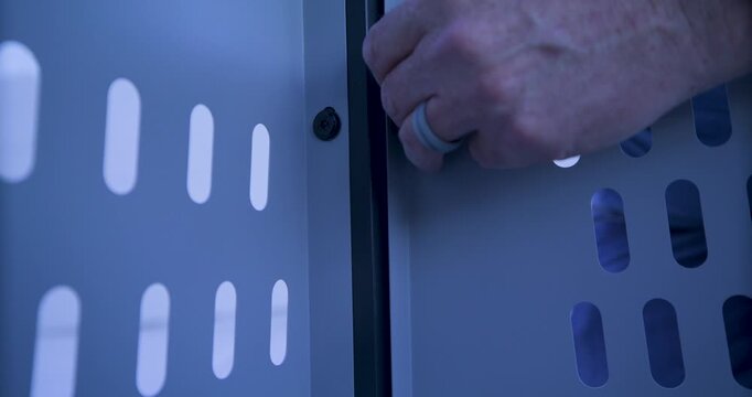 Man's hand twisting screw into metal wall of structure - closeup