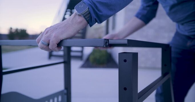 Man placing metal platform on legs of structure - closeup panning shot