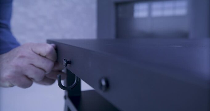 Man screwing screws into metal platform by hand - closeup