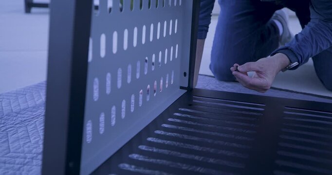 Man's hand putting screw into metal wall of structure - low shot
