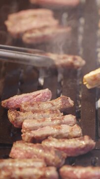 Chef Grilling and Turning Cevapi Sausages on a Barbecue