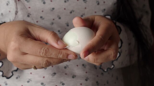 Hands hold white egg in home setting for cooking