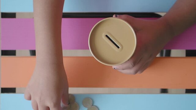 A child places coins into a container while sitting at a table