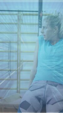 woman tapping smartband display in gym, counting breaths then multiplying, showing animated 24 bpm