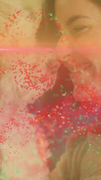 Vertical video: Woman holding dog close sparking nuzzling for petcare while pink flare crosses face