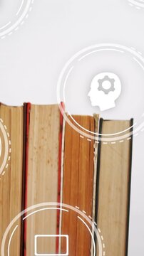 Vertical video: Camera panning book spines centering view while icons pulse over books for learning