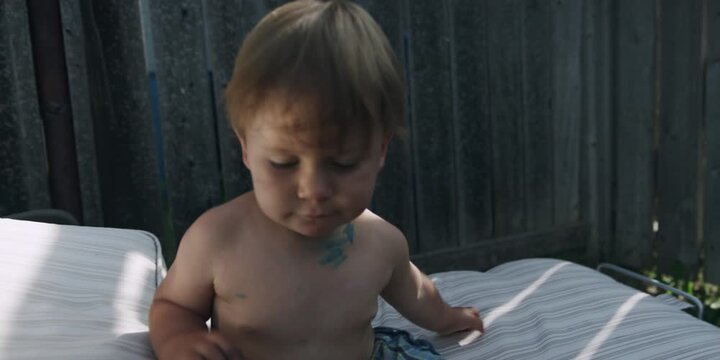 Young boy standing by a sun lounger in a sunny backyard
