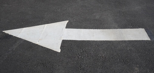 White left arrow painted on asphalt road surface © Simone