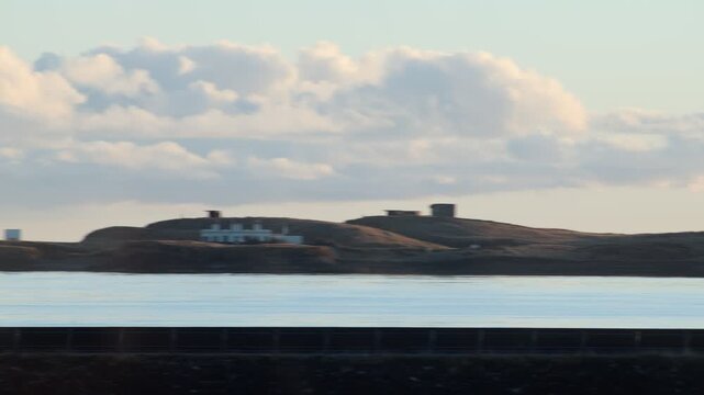Golden hour shot of a lighthouse and a manufacturing plant in Stornoway.