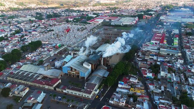 Sugar mill factory processing sugarcane and releasing polluting smoke into the urban environment