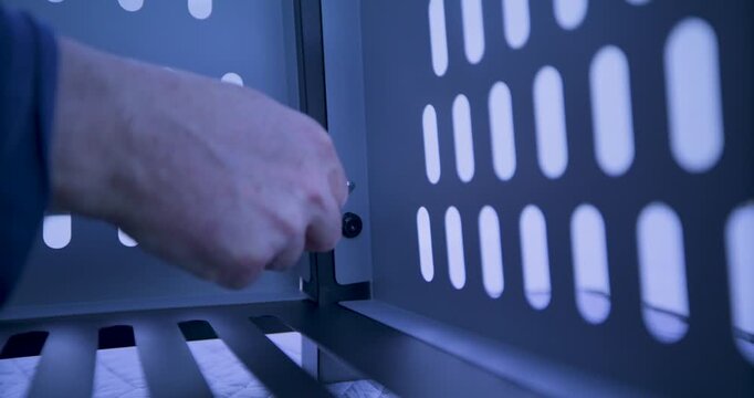 Low shot in metal structure as man's hand tightens screw with small tool