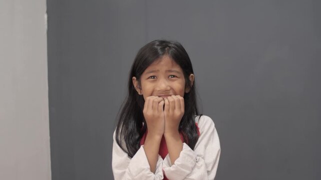 Anxious little Asian girl looking scared and worried, stressed child biting fingers with fearful expression, concept of childhood anxiety, bullying