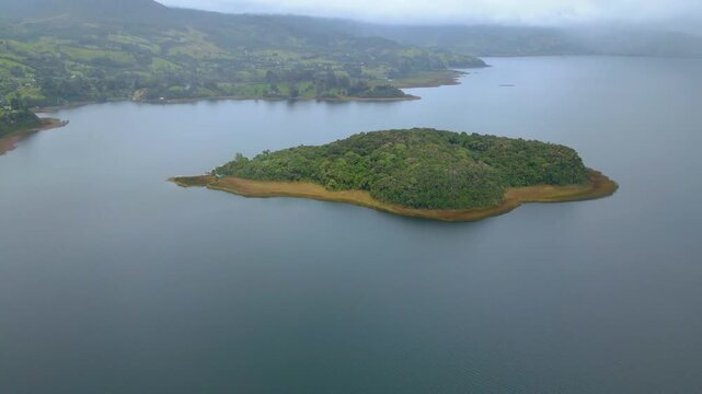A serene aerial shot of Cocha Lagoon showcasing a green island surrounded by calm water under a cloudy sky.