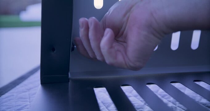 Adult man's hand screwing screw into metal cart - closeup