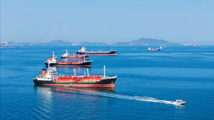 Naklejka premium LPG gas and oil tanker ships anchored in the ocean, with a fast patrol boat in the foreground. Global energy transport, war energy crisis, and Strait of Hormuz blockade concept.