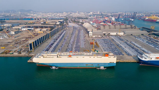massive car carrier and cargo ships docked at a commercial port terminal. Global automotive trade logistics, container freight transport, and commodity supply chain concept.
