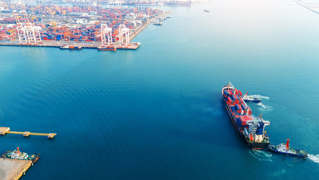 large container ship assisted by two tugboats in the deep blue sea. Global maritime trade logistics, commercial freight transport, and commodity supply chain concept.