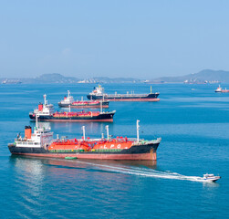 LPG gas and oil tanker ships anchored in the ocean, with a fast patrol boat in the foreground. Global energy transport, war energy crisis, and Strait of Hormuz blockade concept. © Yellow Boat