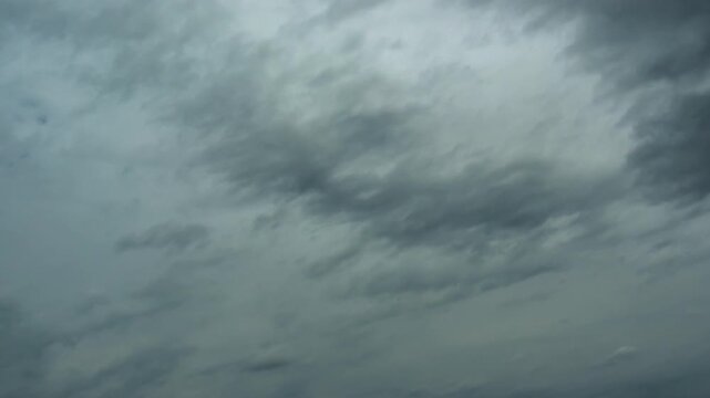 Ominous dark thunderclouds moving fast across the sky, impending rain storm time-lapse.