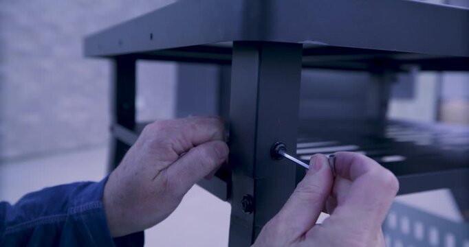 Adult man's hands screwing in screw into metal structure - closeup