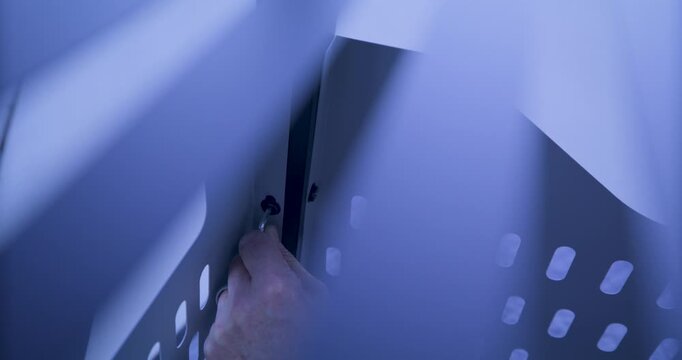 High shot through holes in metal to man's hand screwing screw into cart