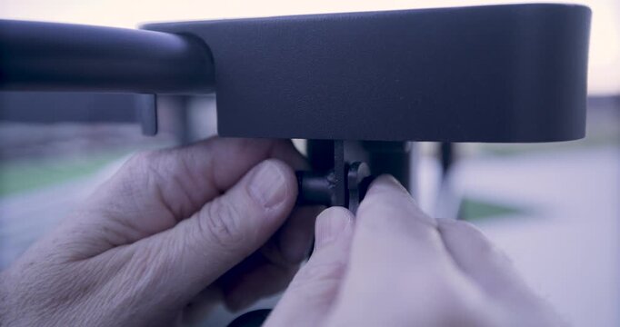 Adult male hands turning knob on metal structure - closeup