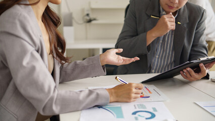 Close up of colleagues reviewing business documents and graphs while using a digital tablet....