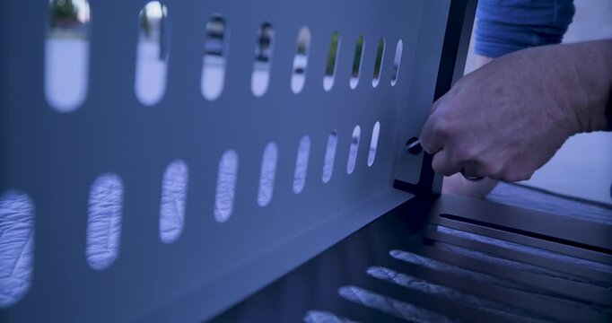 Man screwing screw into interior of metal cart at dusk