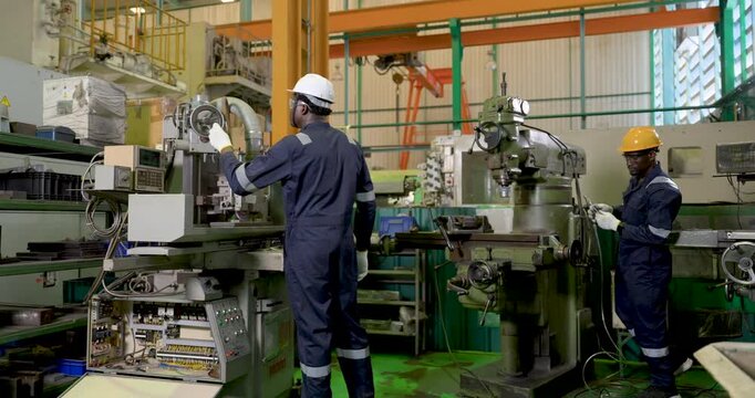 two african adult male workers continue machining tasks across connected workshop line, coordinate machine control and inspection in , safety PPE teamwork drives production efficiency