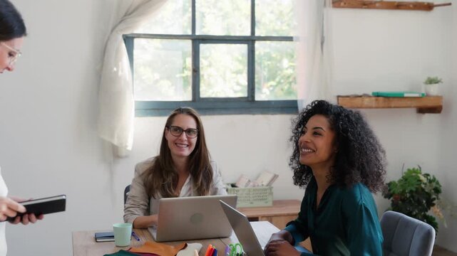 Video of group of fashion designers choosing fabrics while creating new designs on the laptops in a coworking place