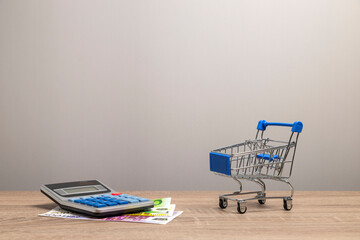 Calculating shopping budget with calculator and miniature cart © Nando Vidal