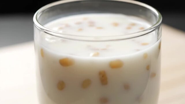 Refreshing milk drink being poured into glass with tapioca pearls