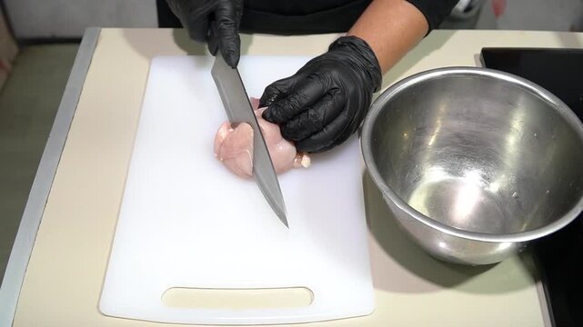 Professional Chef Slicing Fresh Raw Chicken Breast on White Cutting Board