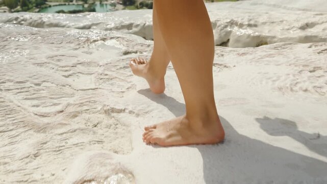 Female legs, she walks on the white calcite deposits on the Pamukkale travertines. Along the edge of the cliff.