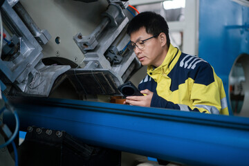 Worker operating industrial equipment to inspect mechanical parts in a factory setting