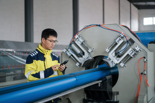 Worker operating pipe processing equipment while checking operational parameters