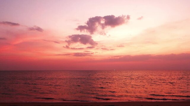 Red pink sunset purple sky over calm ocean wave n sea water with colorful dark rain stom cloud n cumulus cloudscape in twilight sunlight n sun ray at Tropical summer sandy beach, 4k Phuket thailand
