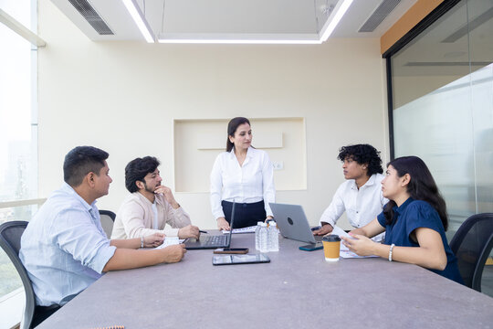 Young indian business people or office employees sitting in meeting room discuss work. Corporate job. Teamwork.