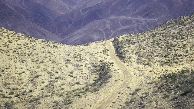 Textured namibia foreground curve toward ridges showing compacted silt and pebble patterns, layered violet hills, scientific survey tone and soft overcast light
