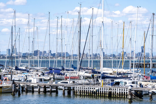 Marina in Williamstown, a suburb in Melbourne, with sailboats moored along the waterfront and the city skyline in the distance. A coastal urban scene reflecting leisure boating, waterfront lifestyle