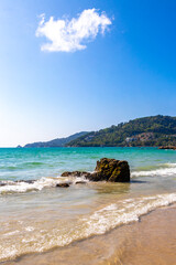 Obraz premium Tropical rocky Kalim Beach turquoise blue water waves rocks Thailand.