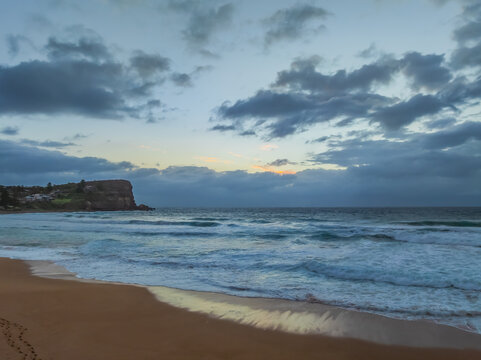 Seaside Sunrise with rolling waves and rain clouds