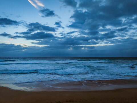 Seaside Sunrise with rolling waves and rain clouds