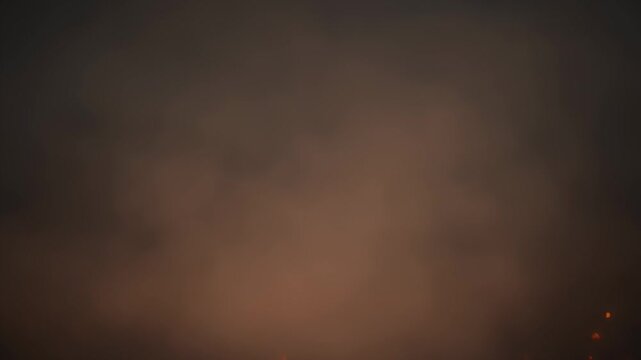 Abstract dark brown smoke texture with warm orange glow and scattered embers below