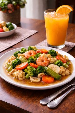 Indonesian Capcay Stir Fry Vegetables with Seafood and Cold Orange Juice on Dining Table