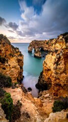 Fototapeta premium Coastal cliffs frame a calm bay under a dramatic, cloudy sky
