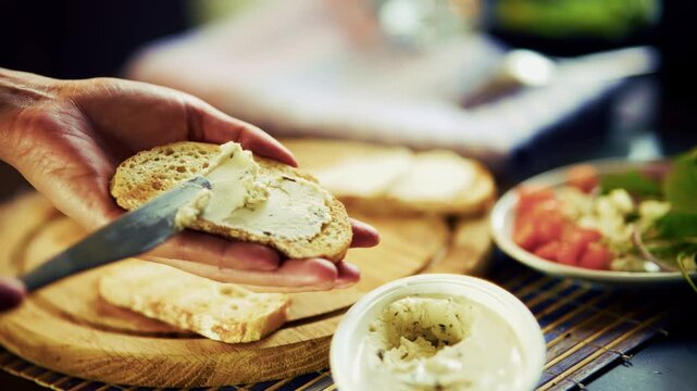 Spreading Cream Cheese On Slice Of Bread Using Knife. Preparing Breakfast Sandwich On Board. Delicious Snack Food 