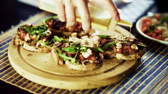 Pouring Olive Oil Over Italian Bruschetta With Tomatoes And Arugula. Mediterranean Cuisine 