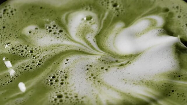 A swirling matcha green tea drink with foamy bubbles and creamy texture