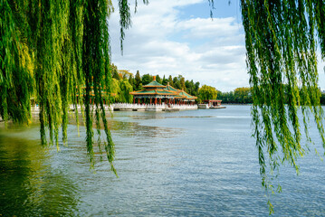 Beihai Park Five Dragon Pavilions with willow trees reflected in lake © KikoStock